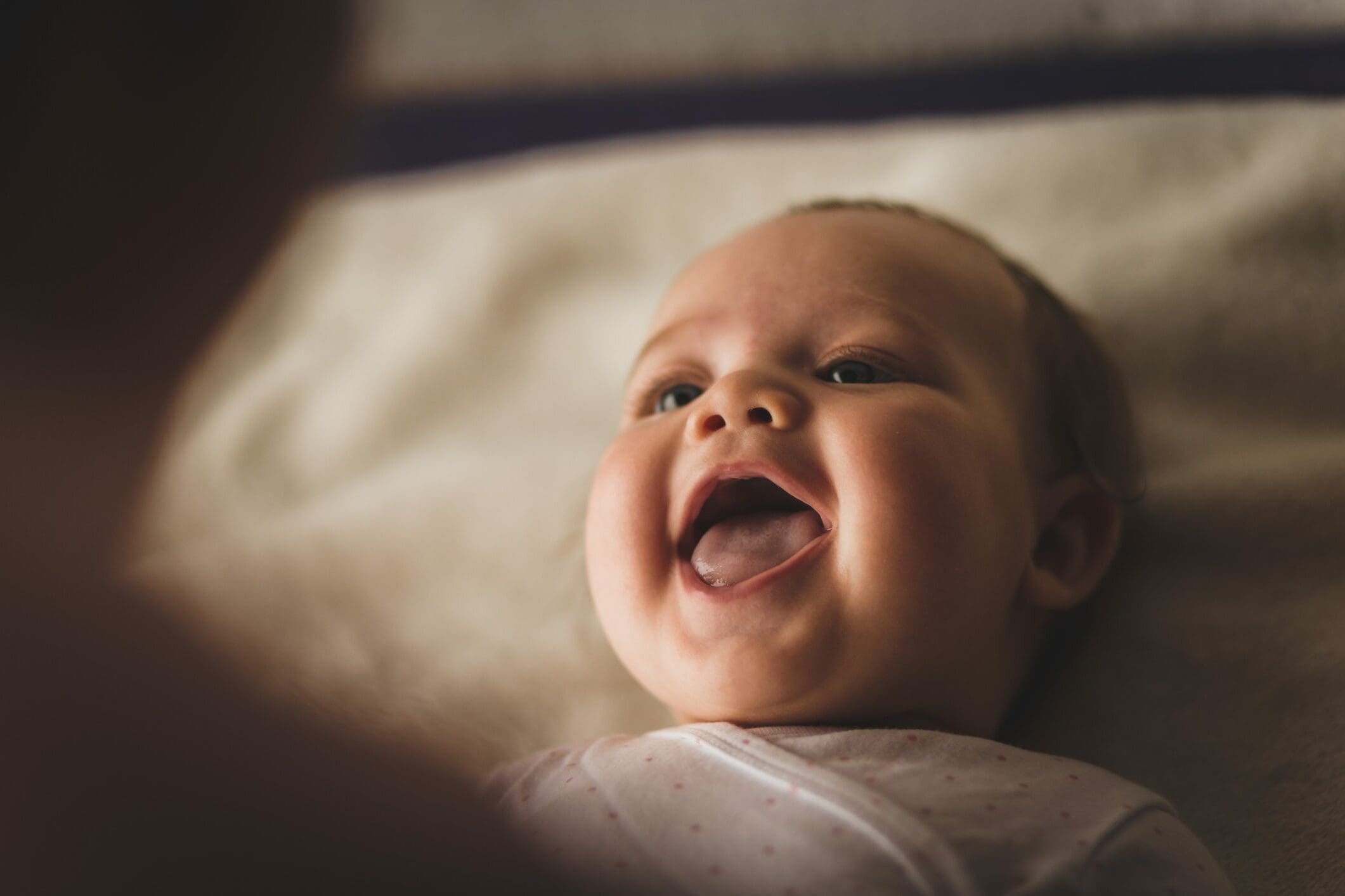 newborn baby girl laughing and giggling while with her mother considers protecting her with child life insurance