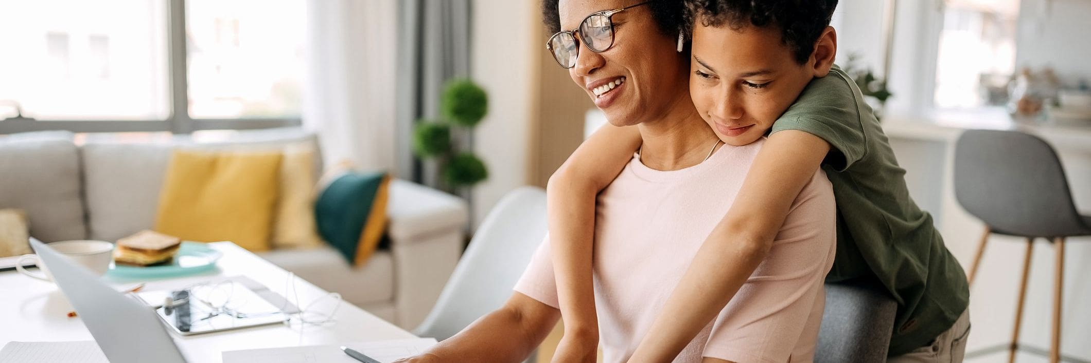 Happy mother working from home hugging with her son